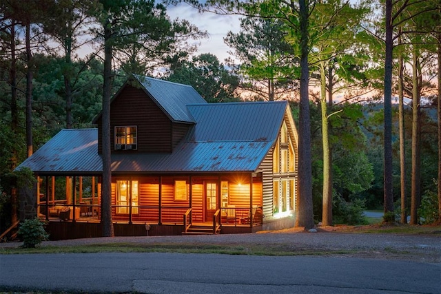 rear view of house with covered porch, faux log siding, and metal roof