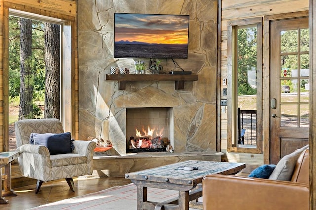 living area featuring plenty of natural light, a stone fireplace, and wood finished floors