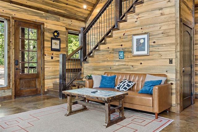 interior space with wooden walls, wooden ceiling, stairs, vaulted ceiling, and concrete flooring