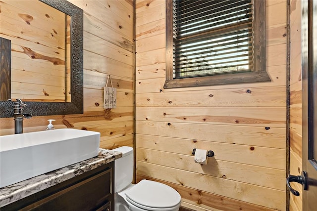 half bathroom with wooden walls, toilet, and vanity