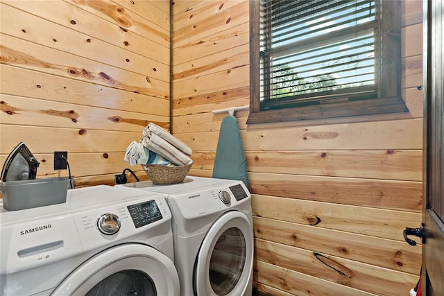 washroom featuring laundry area, wood walls, and independent washer and dryer