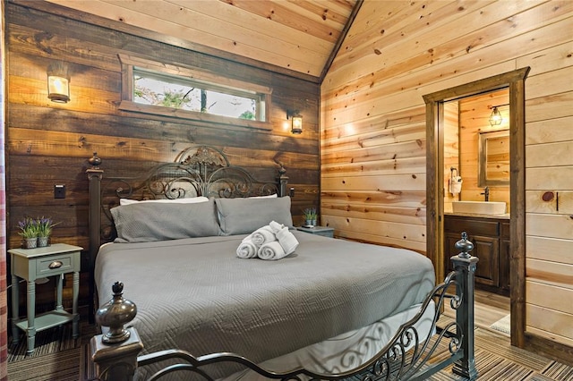 bedroom featuring vaulted ceiling, ensuite bathroom, a sink, and wooden walls