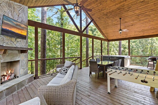 sunroom / solarium featuring vaulted ceiling, a fireplace, wood ceiling, and a ceiling fan