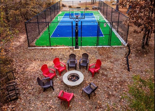 exterior space with a tennis court, fence, and a fire pit