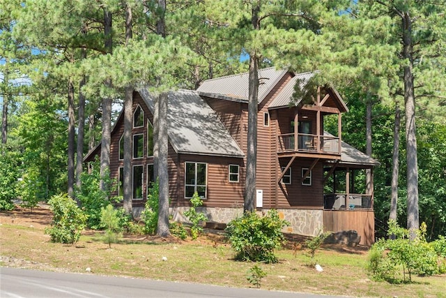 view of side of home featuring a balcony, faux log siding, and metal roof