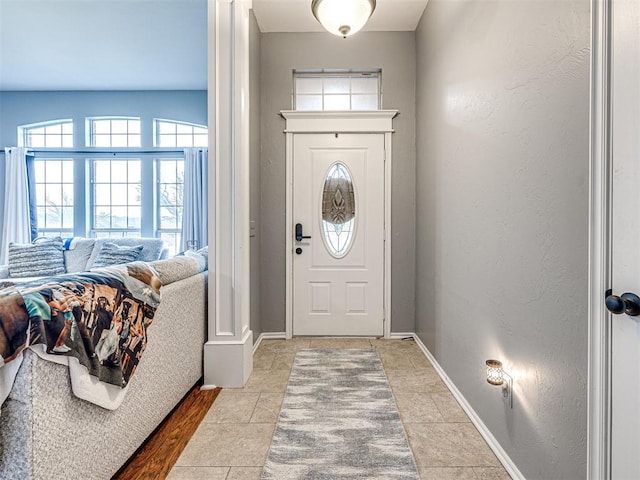 entrance foyer featuring a textured wall and baseboards