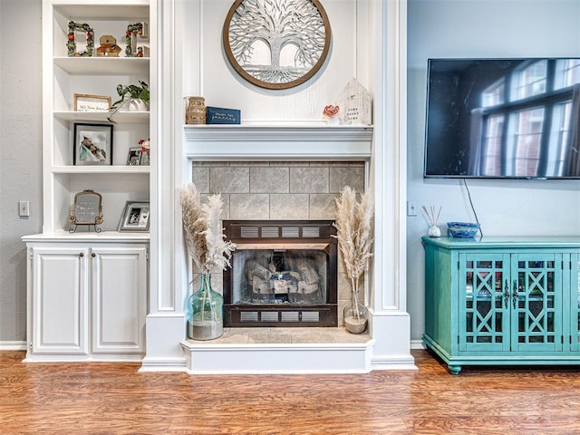 interior details with a tiled fireplace and wood finished floors