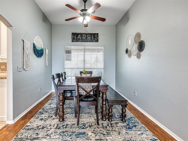 dining area with arched walkways, baseboards, and wood finished floors