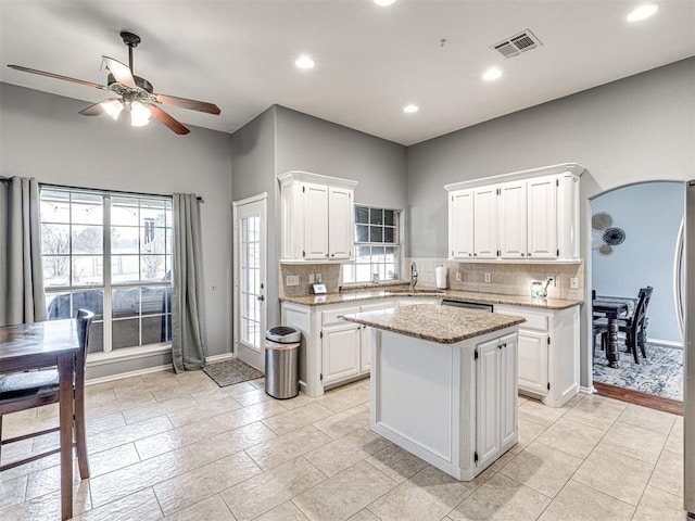 kitchen featuring white cabinets, visible vents, arched walkways, and a sink