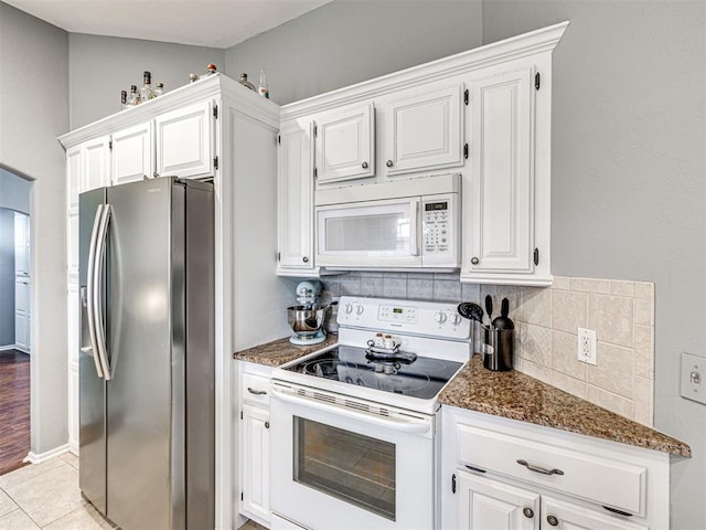 kitchen with white appliances, light tile patterned floors, decorative backsplash, and dark stone countertops