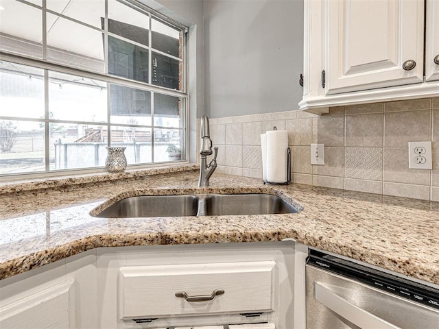 kitchen featuring a sink, white cabinetry, backsplash, light stone countertops, and dishwasher