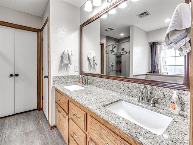 full bathroom featuring double vanity, a sink, visible vents, and a shower stall