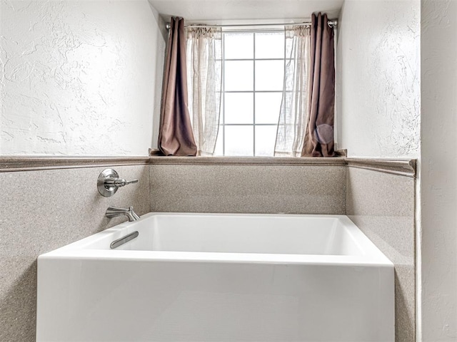 full bathroom featuring a garden tub and a textured wall