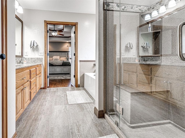 full bath featuring a stall shower, a ceiling fan, ensuite bath, wood finished floors, and vanity