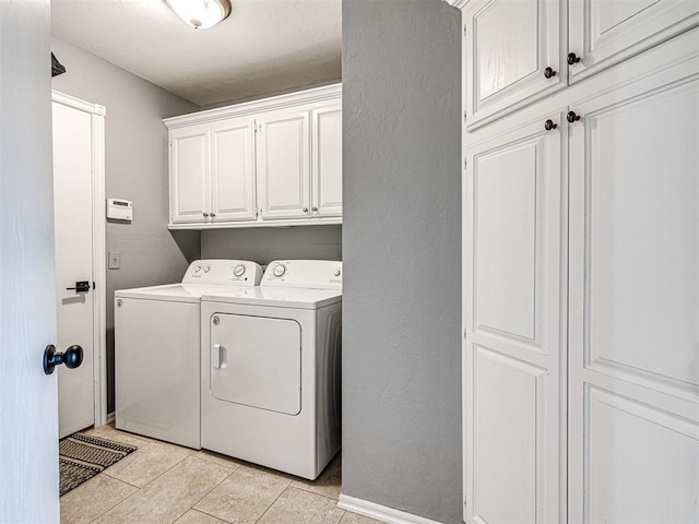 laundry area with light tile patterned floors, cabinet space, a textured wall, washer and dryer, and baseboards