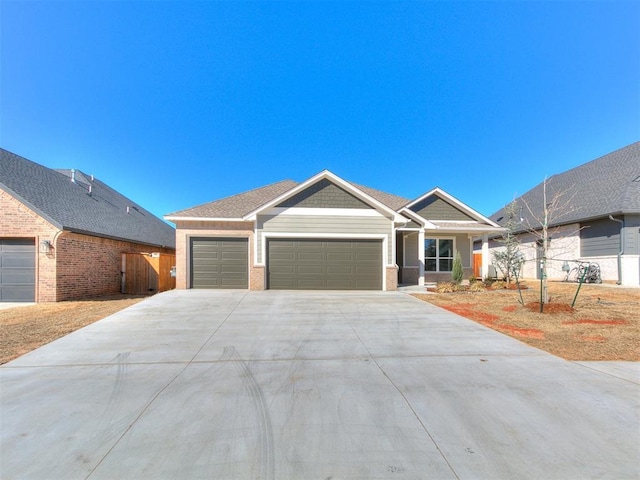 craftsman house featuring a garage, fence, concrete driveway, and brick siding