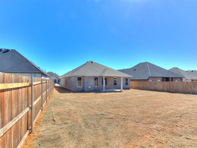 back of property with a fenced backyard, a lawn, and brick siding