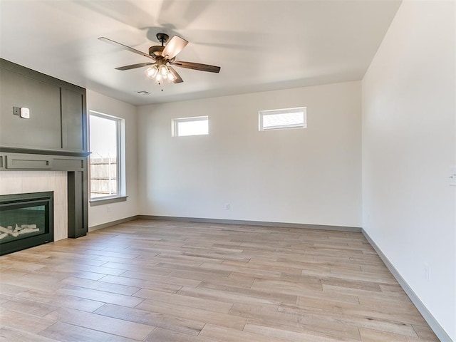 unfurnished living room featuring light wood-style flooring, a fireplace, baseboards, and ceiling fan