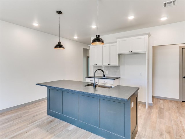 kitchen featuring dark countertops, visible vents, backsplash, white cabinetry, and a sink