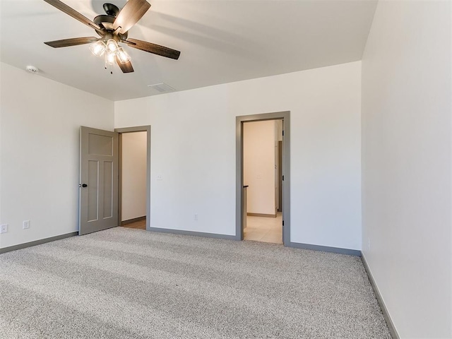 spare room featuring light carpet, ceiling fan, visible vents, and baseboards