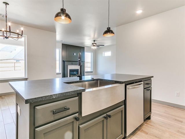 kitchen featuring dark countertops, light wood-style floors, stainless steel dishwasher, and a glass covered fireplace