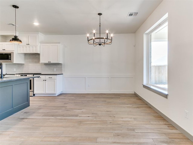 kitchen with stainless steel gas stove, tasteful backsplash, visible vents, and built in microwave