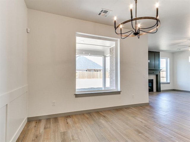 unfurnished room with light wood-type flooring, a large fireplace, and visible vents