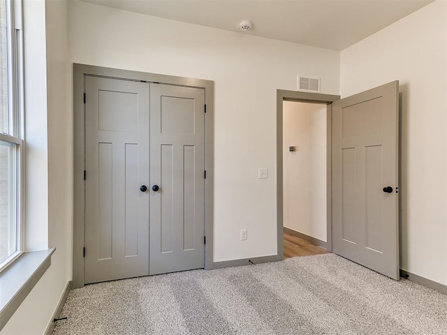 unfurnished bedroom with light carpet, multiple windows, visible vents, and a closet