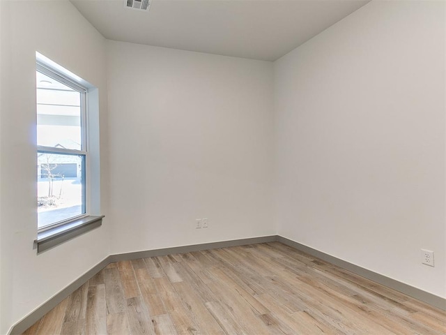 empty room featuring baseboards, visible vents, and light wood finished floors