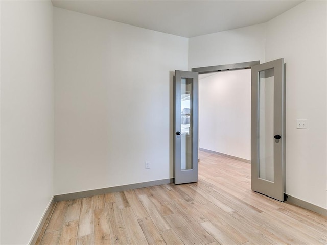 unfurnished room with baseboards, french doors, and light wood-style floors