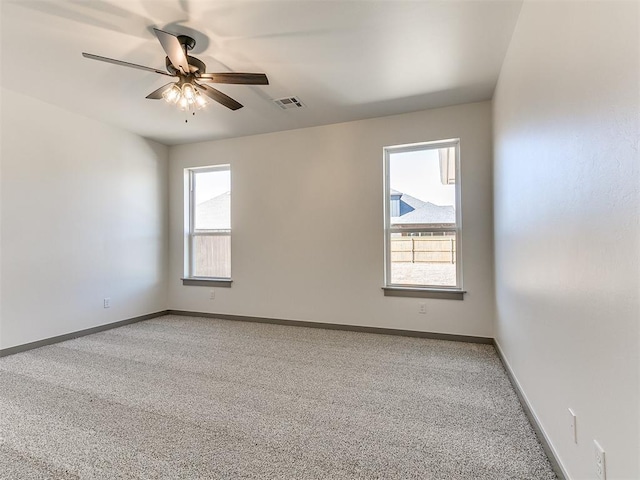 spare room with visible vents, ceiling fan, light carpet, and baseboards