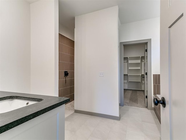 bathroom featuring a spacious closet, vanity, and walk in shower