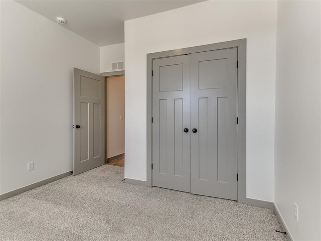 unfurnished bedroom featuring light carpet, a closet, visible vents, and baseboards