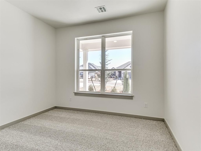 spare room with carpet flooring, visible vents, and baseboards