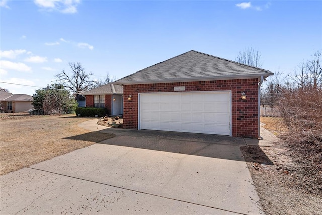 view of front facade with a garage, driveway, brick siding, and roof with shingles