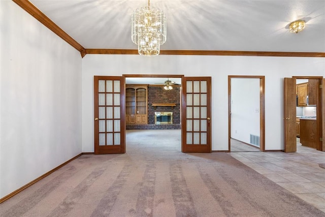 carpeted empty room with ornamental molding, a brick fireplace, french doors, and visible vents