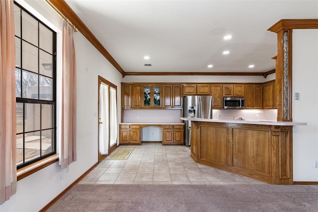 kitchen with light carpet, appliances with stainless steel finishes, brown cabinetry, and built in study area