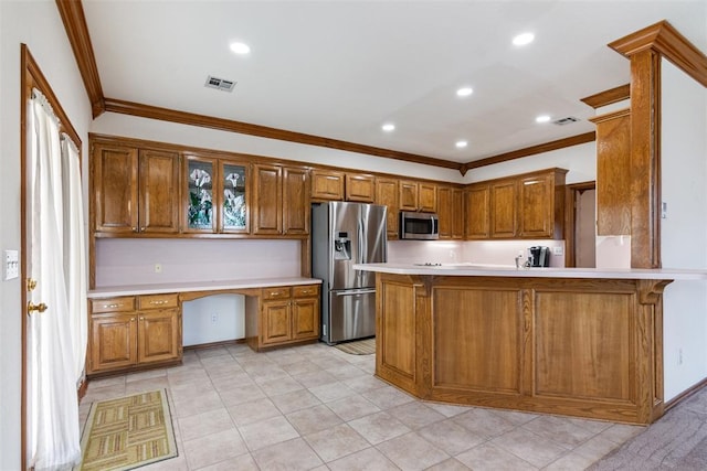 kitchen with appliances with stainless steel finishes, brown cabinets, built in study area, and visible vents