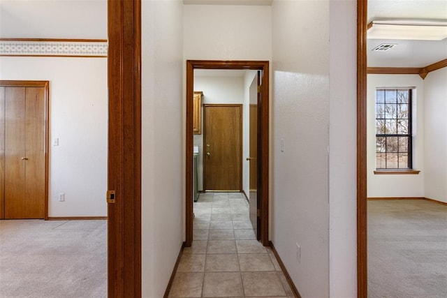 hallway with baseboards and light colored carpet