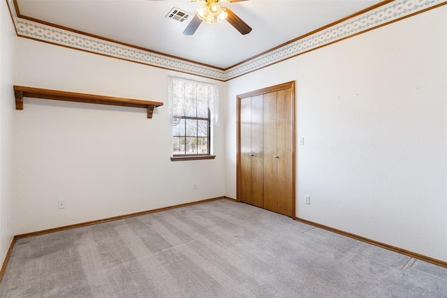 spare room featuring ornamental molding, visible vents, ceiling fan, and carpet floors