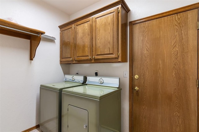 washroom featuring washer and clothes dryer, cabinet space, and baseboards