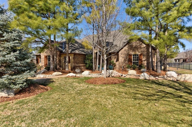 view of front of property with brick siding, a front yard, and fence