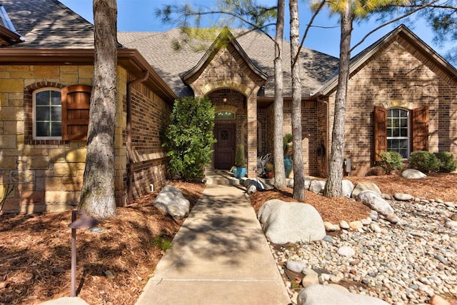 view of front of property with stone siding, brick siding, and a shingled roof