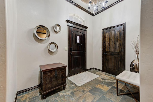 foyer featuring a chandelier, baseboards, and stone tile floors