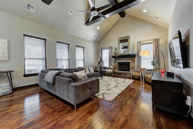 living area with a brick fireplace, visible vents, beam ceiling, and wood finished floors