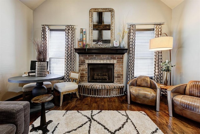 sitting room featuring vaulted ceiling, a fireplace, and wood finished floors