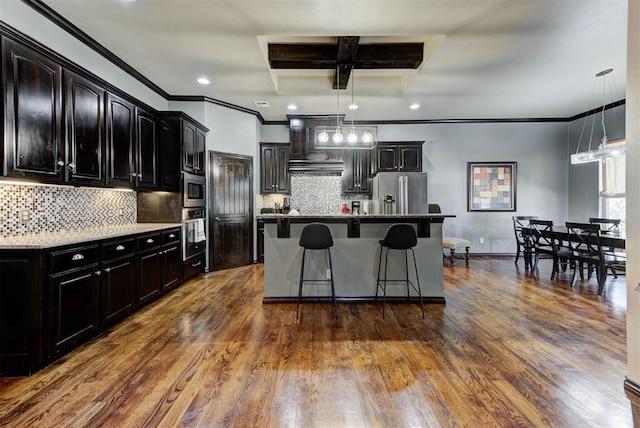 kitchen with a kitchen breakfast bar, dark wood-style flooring, a center island, decorative light fixtures, and stainless steel appliances