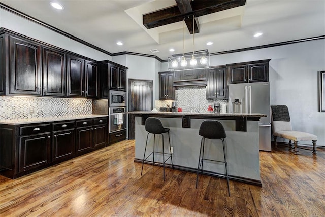 kitchen with a kitchen island, appliances with stainless steel finishes, a kitchen breakfast bar, wood finished floors, and hanging light fixtures