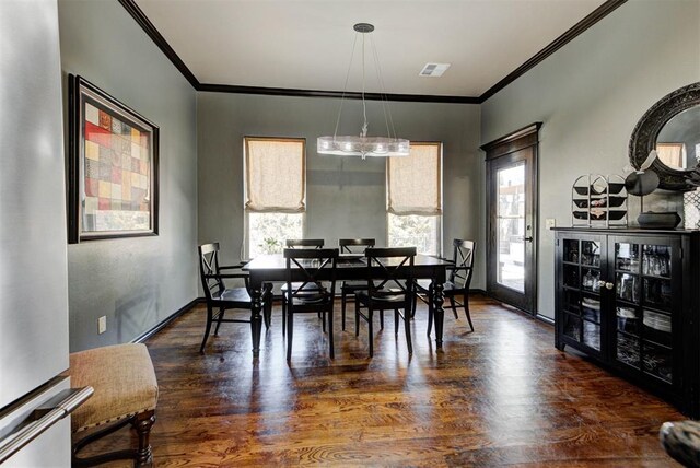 dining area with baseboards, wood finished floors, visible vents, and crown molding