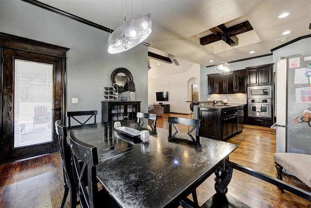 dining area with arched walkways, recessed lighting, coffered ceiling, wood finished floors, and ornamental molding